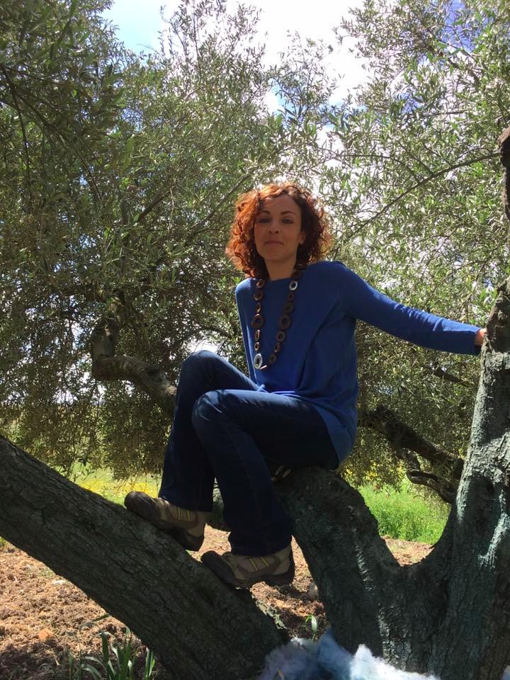 Una donna arrampicata su un olivo