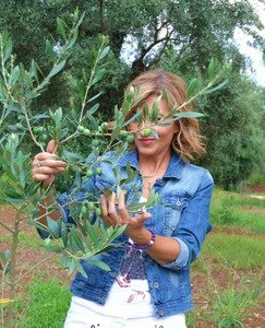 Una donna nascosta dai rami di un olivo